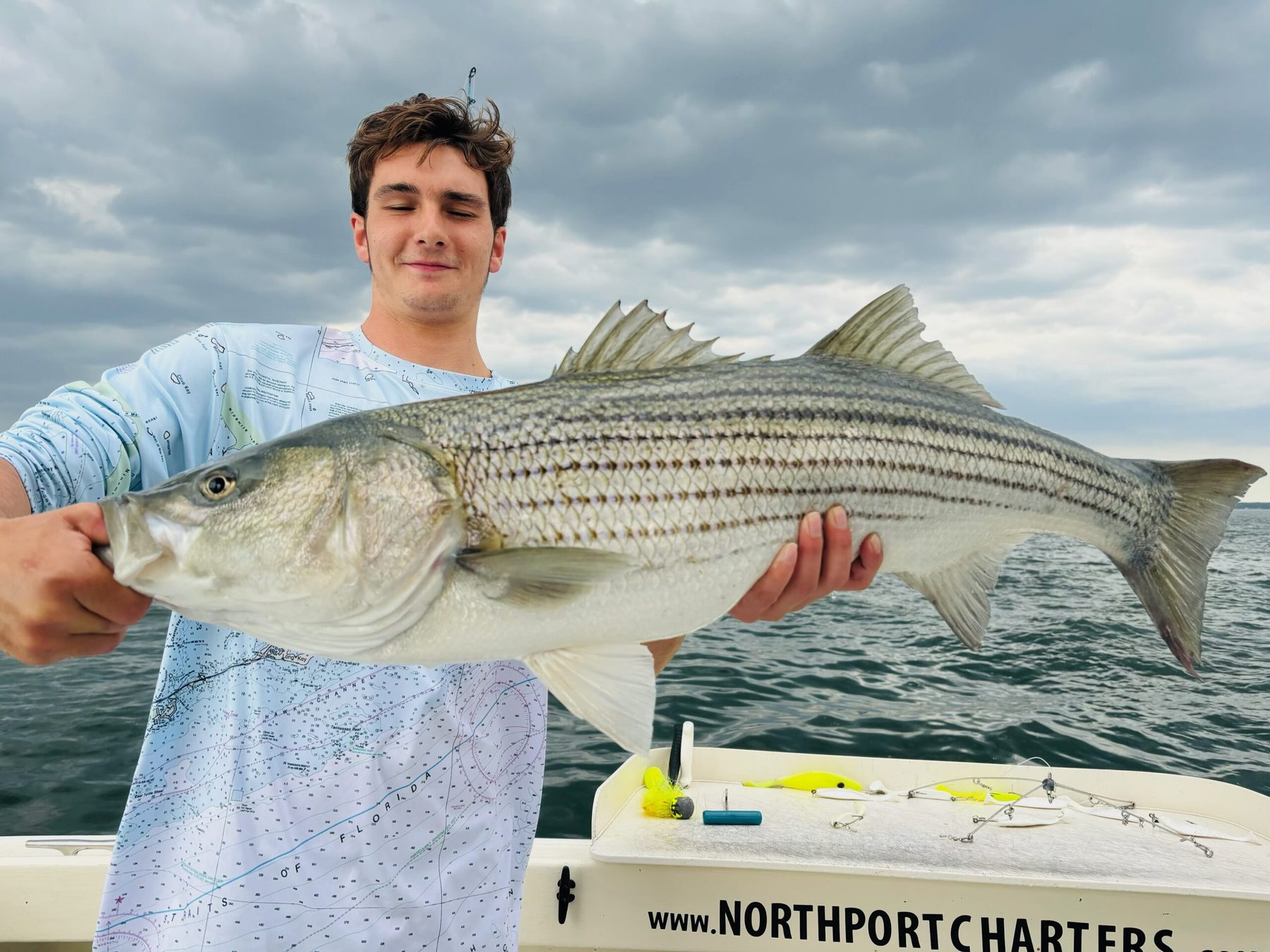 A heavy striped bass held up on the deck of Sashimi