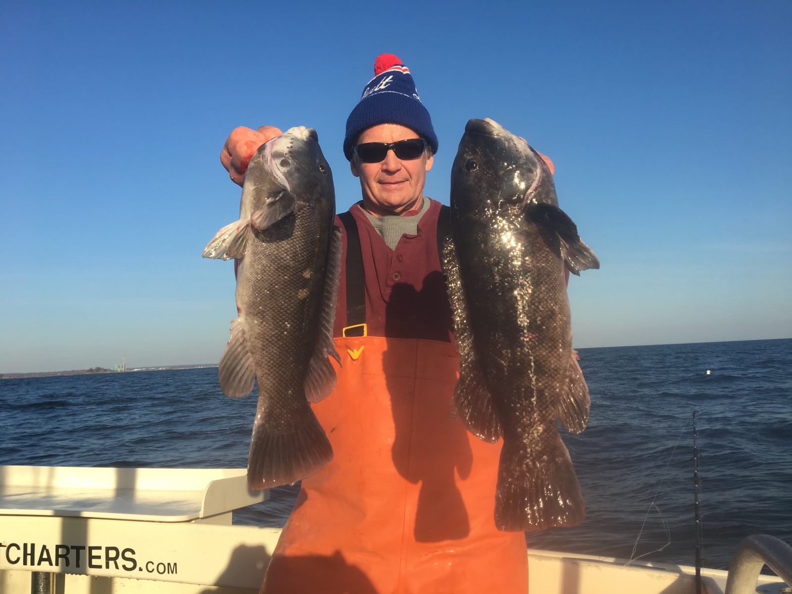 An angler with a blackfish in each hand