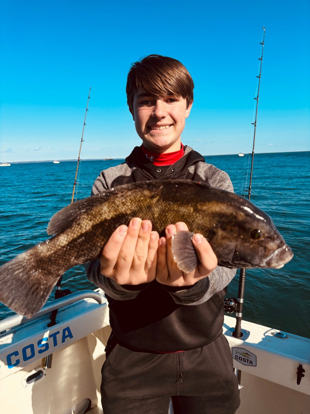 A young angler holding up a blackfish on Long Island Sound