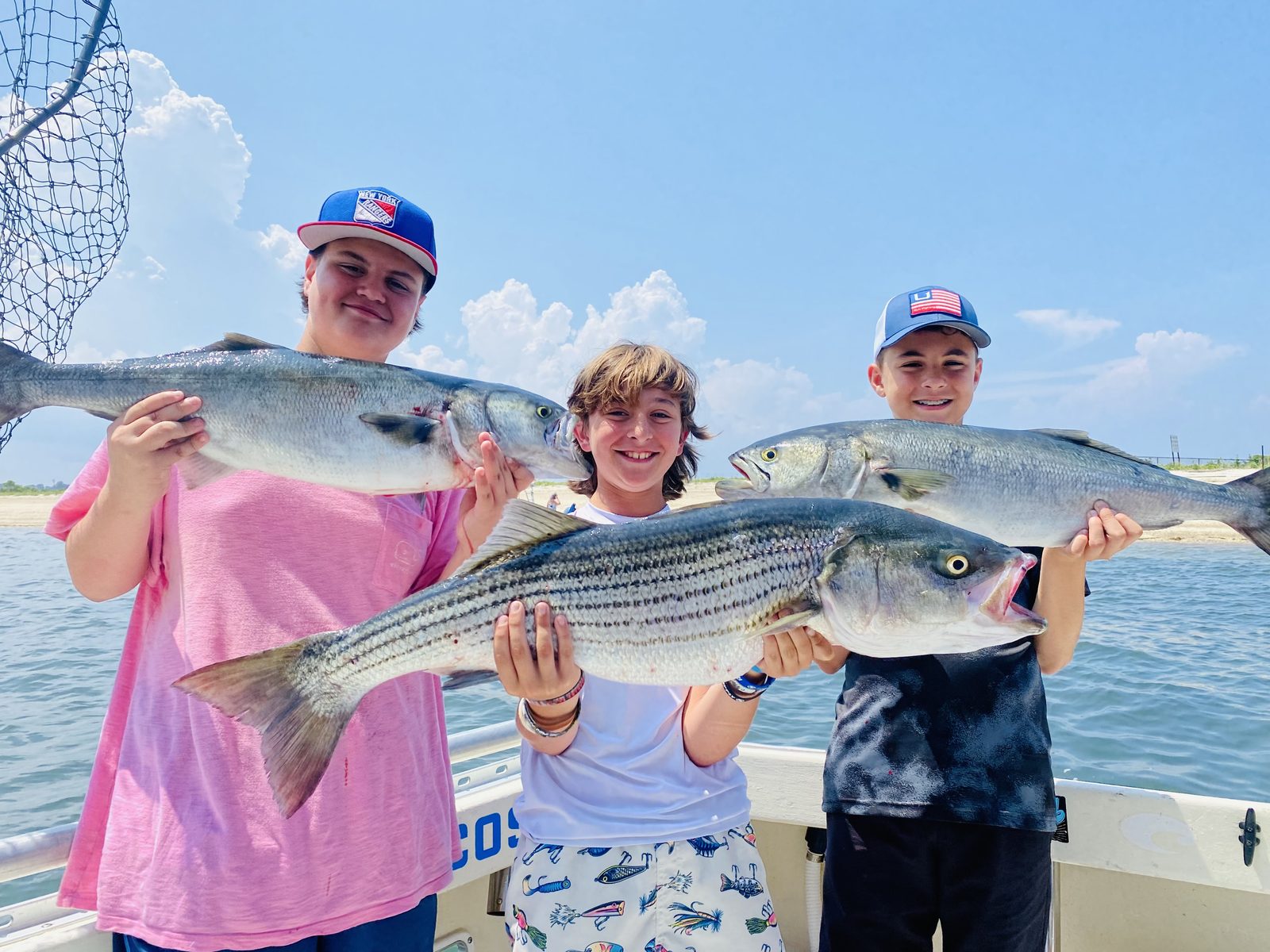 Three campers with striped bass and bluefish