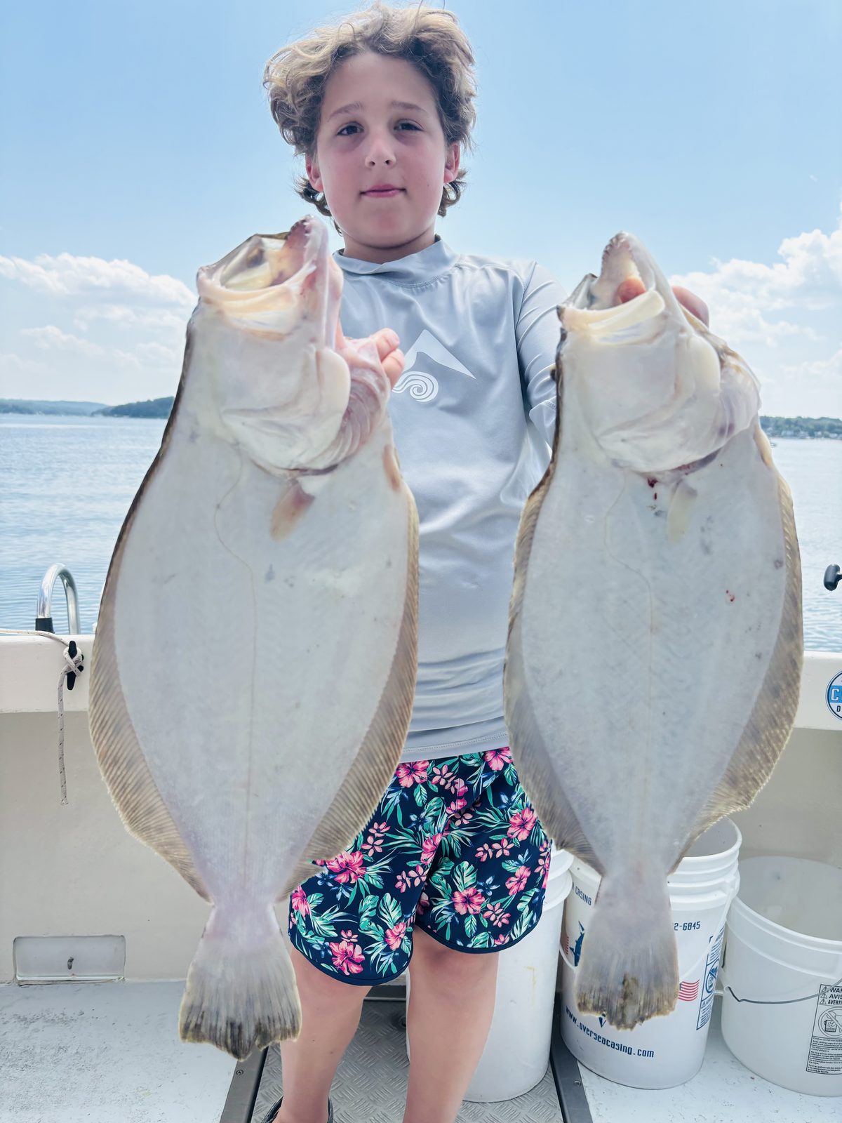 A young angler holding up two fluke