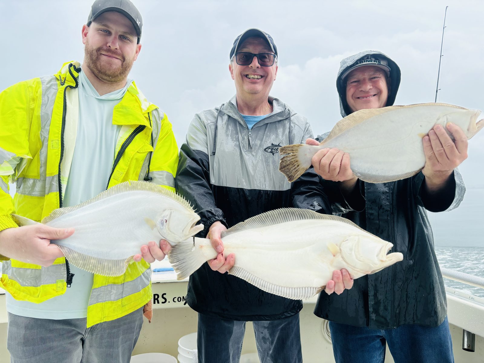 Three anglers in rain gear with fluke