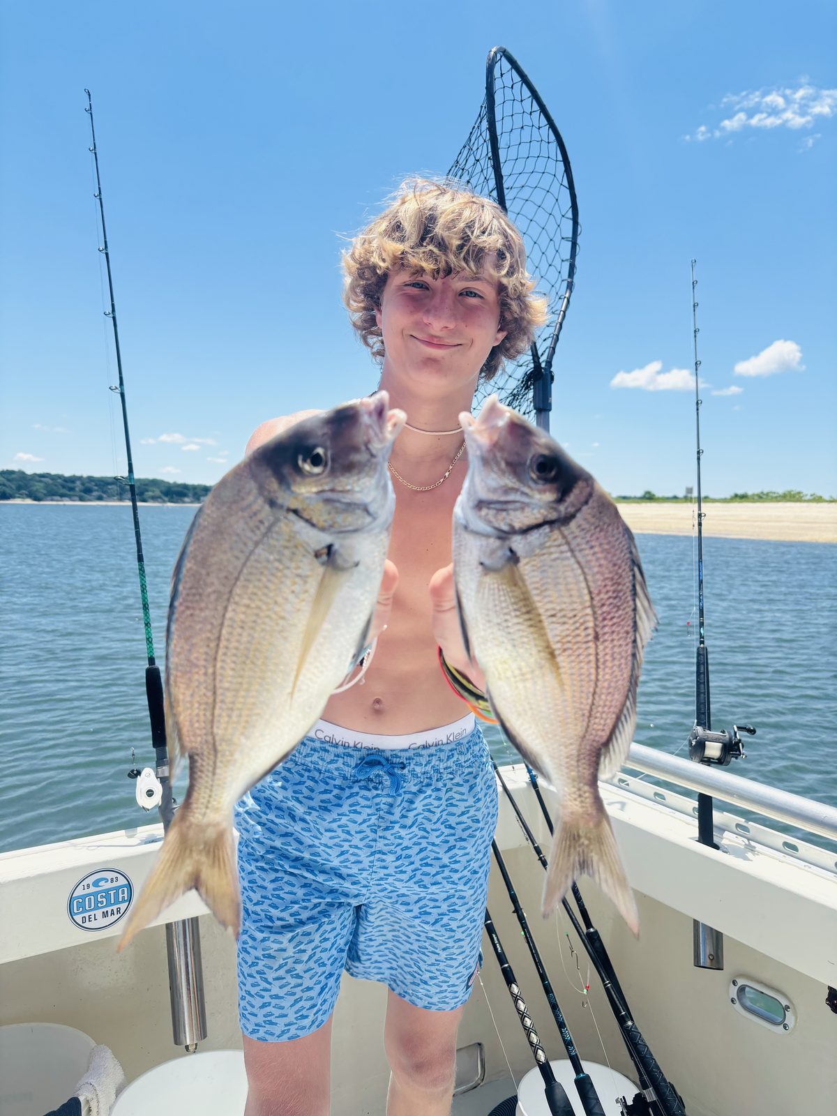 A young angler holding up two big porgies