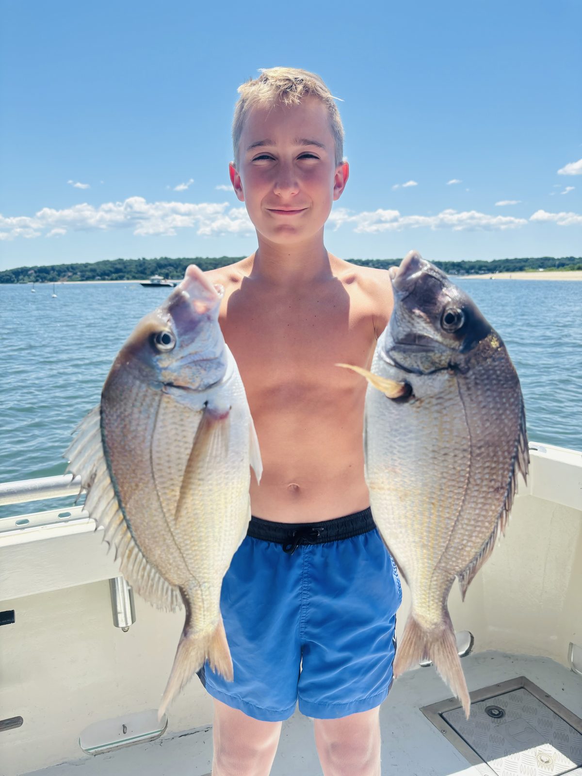 A young angler with a porgy in each hand