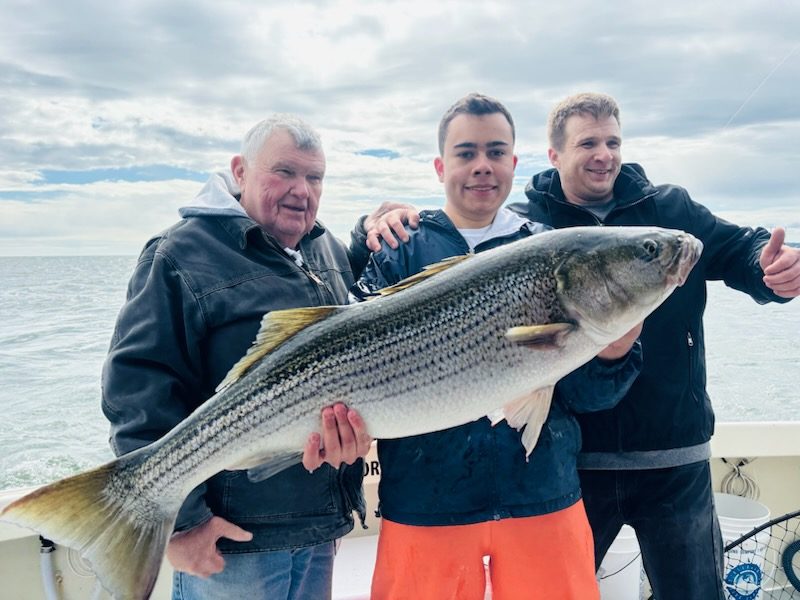 Three anglers with a striped bass on Long Island Sound