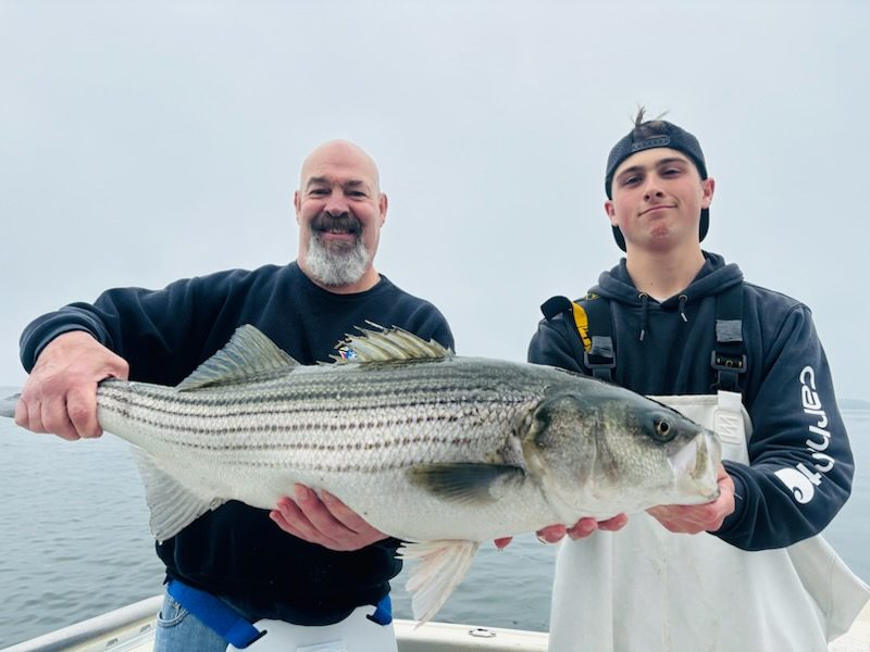 A pair of anglers with a striper at the rail